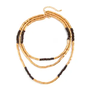 Close-up of triple-layered necklace with gold textured tubes and brown beads