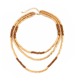 Detail of three-layered necklace with gold textured metal tubes and brown beads.