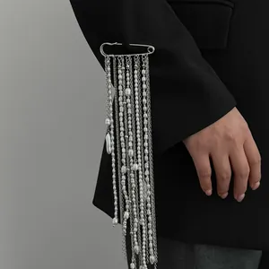 Detail of fashion safety pin brooch with long pearl tassels on black blazer sleeve