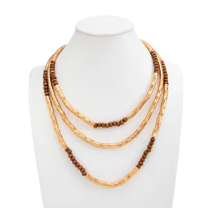 Macro view of textured gold-tone metal and brown bead layered necklace on mannequin