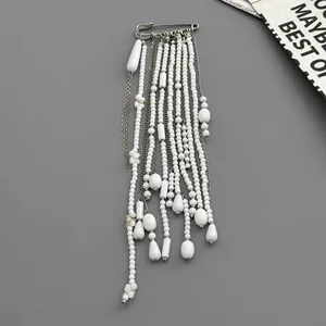 Detailed view of elegant long tassel brooch with white faux pearls and silver chains