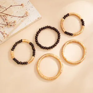 Detailed view of bohemian bracelets with golden metal tubes and dark wood beads.