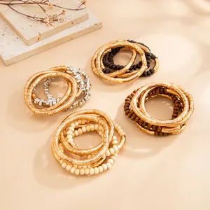 Close-up of textured metallic stacked rings and beaded bracelets in gold and neutral tones