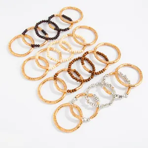 Close-up view of textured metallic rings and colorful beaded necklaces for layering