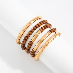 Detail view of layered gold-tone textured metal and brown wooden bead jewelry stack.