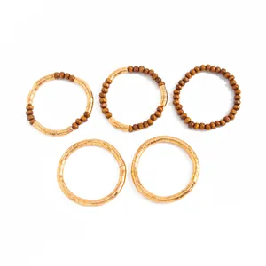 Set of gold textured metallic chokers and brown beaded necklaces on white background