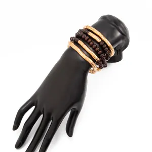 Close-up of multi-layered gold and brown beaded bracelets on a black display hand prop