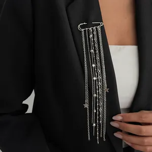 Close-up of an elegant silver safety pin brooch with long tassel chains and stars.