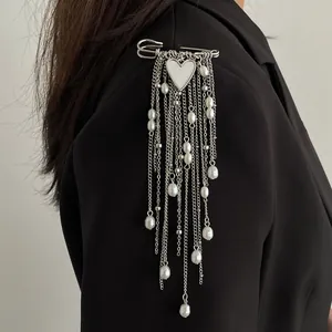 Detail shot of a silver-tone heart brooch with dangling faux pearl chains on a blazer.