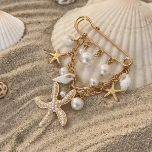 Macro detail view of beach themed gold brooch with starfish, conch and imitation pearls