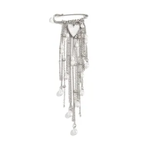 Detail view of a silver heart pendant brooch with multiple faux pearl chain tassels
