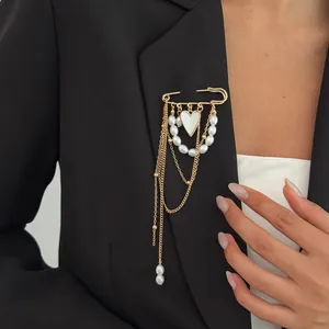 Elegant gold safety pin brooch with white heart pendant and pearls on black blazer