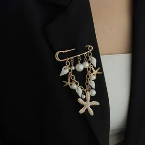 Gold safety pin brooch with starfish, seashell charms and faux pearls on black blazer
