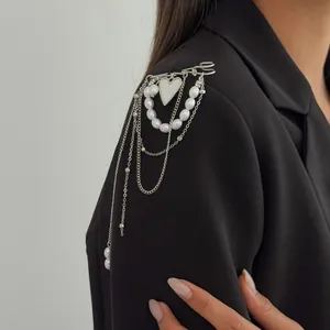 Detailed view of silver heart brooch with imitation pearls and multi-layered chains.