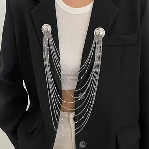 Détail en gros plan d'une broche à chaîne à pompons multicouches avec perles blanches
