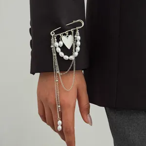 Close-up of a silver heart pearl brooch with multi-layer chains on a blazer sleeve.