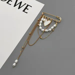Detailed view of golden multi-layer chain brooch with faux pearls and white heart pendant