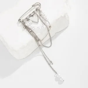 Close-up of the silver safety pin brooch featuring faux pearls and dangling heart