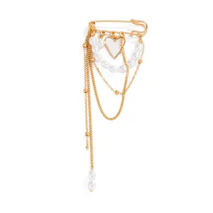 Detail view of a gold safety pin brooch with layered pearl chains and heart charm