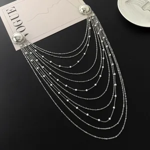 Vue détaillée de la broche à chaînes à pompons argentées multicouches avec perles sur fond noir