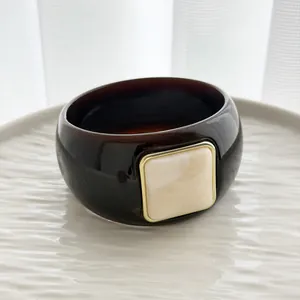 Detailed shot of a vintage dark brown resin bangle featuring a square cream stone accent