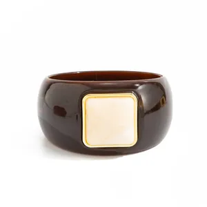 Macro detail of retro marbled resin bangle with decorative square gold-tone inlay