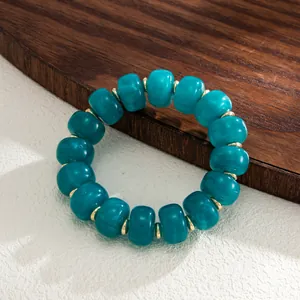 Detailed view of bohemian marbled teal resin beads with golden stainless steel spacers
