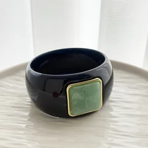 Close-up of vintage marbled resin bangle with square green accent and gold frame.
