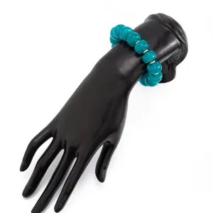 Detailed shot of a bohemian teal resin beaded bracelet on a black hand display stand