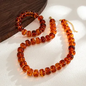 Close-up detail of amber resin beaded necklace and bracelet set with golden spacers