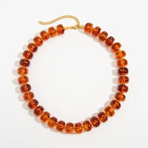 Close-up detail of bohemian amber resin beaded necklace with gold stainless steel chain