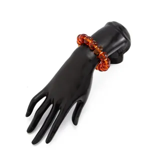 Macro detailed view of bohemian amber resin beaded bracelet on a black display hand model
