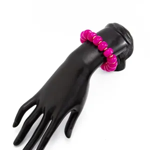 Detailed view of vibrant pink resin beads with gold accents on a black display hand.