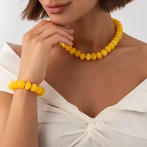 Elegant close-up view of bohemian yellow resin beaded necklace and bracelet set on a model