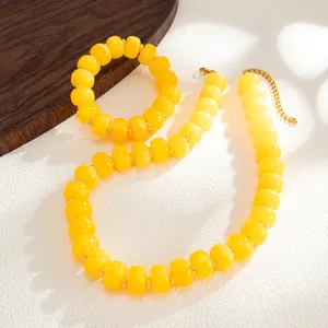 Close-up of yellow resin bead necklace and bracelet set with golden chain
