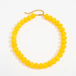 Close-up of a vibrant yellow resin bead necklace with a gold stainless steel chain.