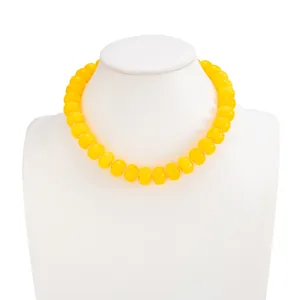 Macro detail of glossy yellow resin beads on a bohemian style stainless steel necklace