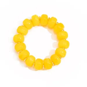 Close-up detail of yellow resin barrel beads with gold spacers on a white background