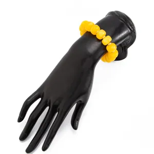 Detail view of a bohemian yellow resin beaded bracelet displayed on a black mannequin hand