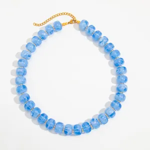 Detail of blue marbled resin beads and golden stainless steel chain necklace