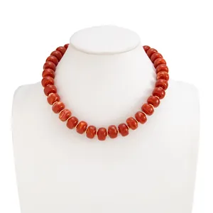 Detailed macro view of bohemian style orange marbled resin bead necklace with steel accents.