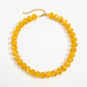 Close-up of bohemian yellow swirl resin beads on stainless steel necklace chain.