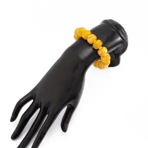 Detail showing yellow resin beads with bohemian style on a black jewelry hand display stand.