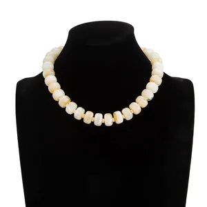 Detailed view of marbled resin bead necklace with golden spacers on black mannequin.
