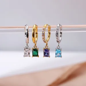 Primo piano di orecchini a cerchio con zirconi rettangolari 4x6mm, finiture oro e argento.
