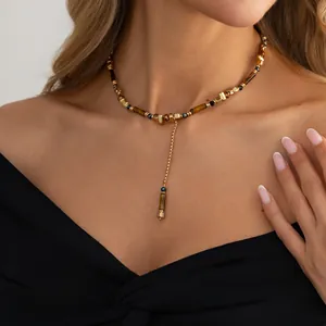 Detailopname van Y-vormige ketting met tijgeroog en gouden onregelmatige kralen.