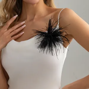 Close-up of elegant black feather brooch pinned on a white silk evening dress detail