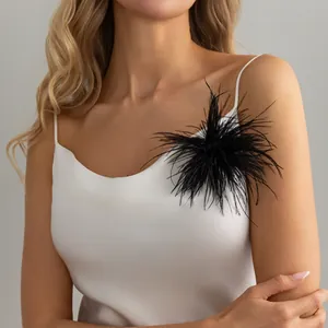 Close-up detail showing a black feather brooch accessory on a white satin slip dress