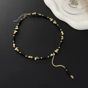 Detailopname van een elegante Y-choker met zwarte kralen en goudkleurige blokjes