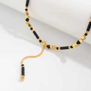 Gedetailleerd beeld van de Y-ketting met zwarte kristallen en gouden kubus kralen